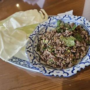 LARB [GLV] beef seasoned with mint leaves, scallion, hot peppers, and fresh lime juice. Served with cabbage.