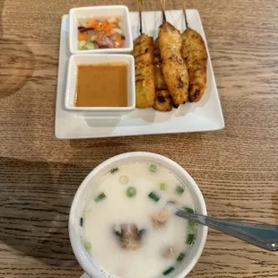 a bowl of soup and skewers