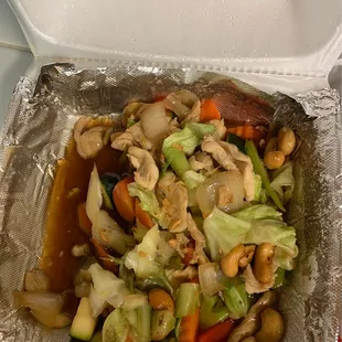 a takeout container with a mixture of vegetables and cashews