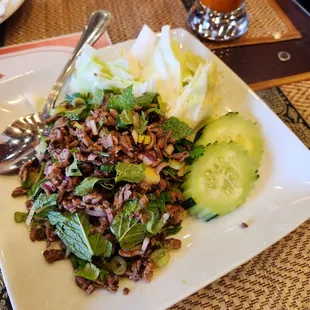 Larb salad with beef (has mint, cilantro and green onion alongside cucumbers on top of a cabbage bed) is uniquely Laotion and tasty.