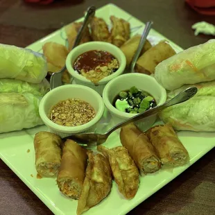 a plate of spring rolls with dipping sauces