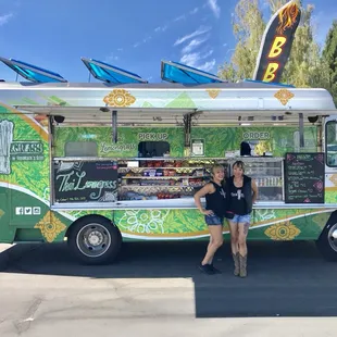 two women standing in front of a food truck