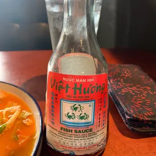 a bowl of soup and a bottle of hot sauce