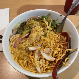 Egg noodles and chicken in a rich creamy coconut curry, red onion, pickled mustard greens and crispy noodles.