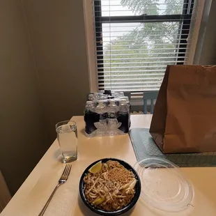 a bowl of noodles and a glass of water