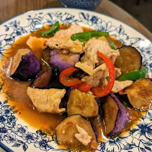 E8. Pad Eggplant. $13.95. Pork (+$1) stir-fried with chili, garlic, bell peppers, Thai basil and eggplant. Comes with bowl of rice.