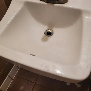 The men's room sink is coated with months of dirt and grease.