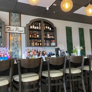 a bar with stools and bottles of alcohol