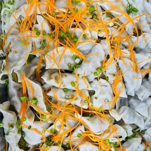 a tray of dumplings with shredded cheese