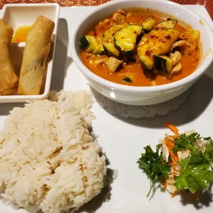 a bowl of rice, a bowl of vegetables, and a plate of fried egg rolls