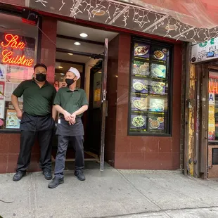 two men standing in front of a restaurant