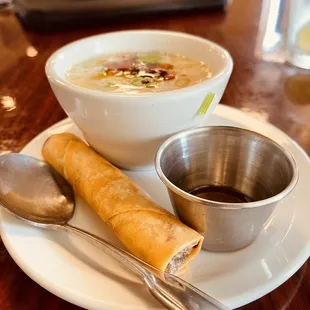 a bowl of soup and a roll on a plate