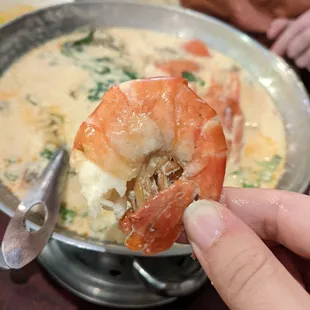 a hand holding a piece of shrimp