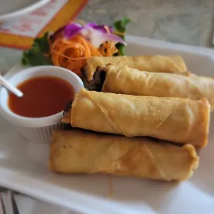 a plate of spring rolls with dipping sauce