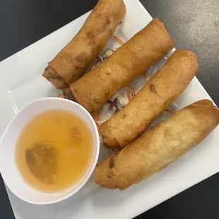 a plate of fried spring rolls with dipping sauce