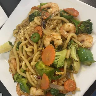 a plate of noodles with shrimp and vegetables