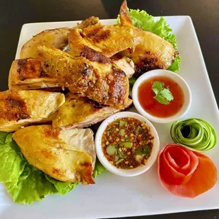 a plate of grilled chicken with dipping sauce