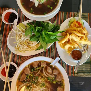 three bowls of soup and a plate of noodles