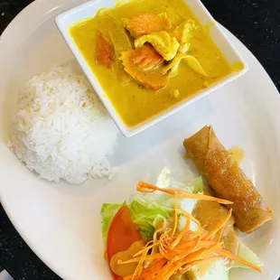 Yellow curry chicken rice plate with egg roll and lettuce salad for lunch
