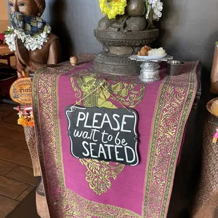 a table with a sign saying please wait to be seated