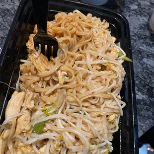 noodles and chicken in a black container