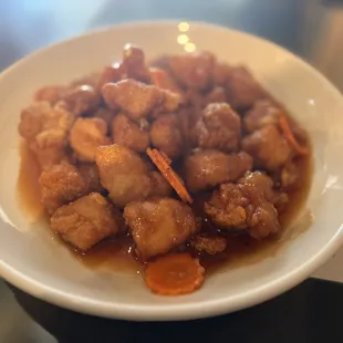 Orange Chicken... Hand breasded chicken breast bites, tossed in out sweet and tangy sauce, carrots, finished with with an orange marmalade..