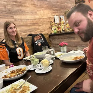 a man and a woman sitting at a table with plates of food
