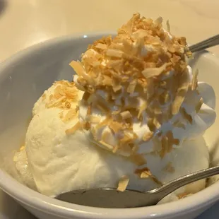 Warm sticky rice topped with coconut ice cream and coconut flakes
