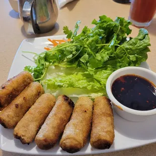 a plate of fried spring rolls with dipping sauce