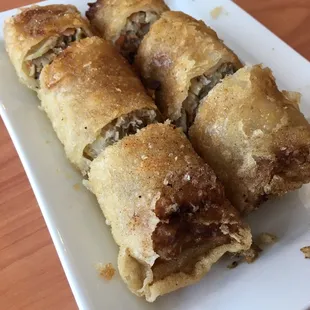 a white plate with three sausage rolls on it
