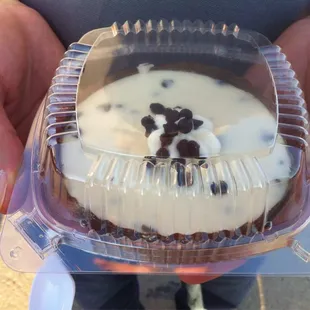 a person holding a container of cheesecake