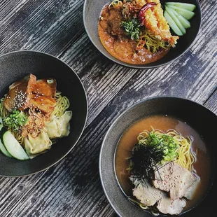 three bowls of food on a wooden table