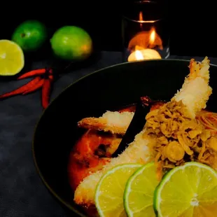 a bowl of food with limes and a candle