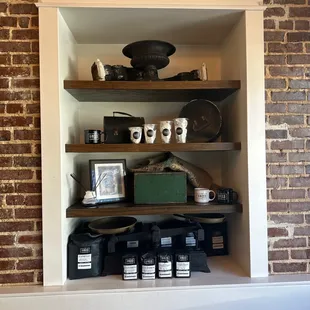 a brick wall and shelves with coffee mugs