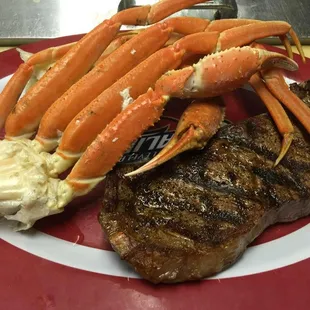 a steak, crab legs and carrots