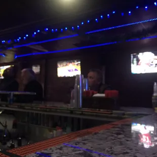 people sitting at a bar watching tvs