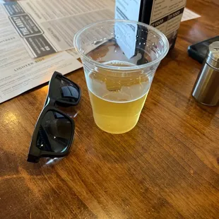 a cup of beer and sunglasses on a table