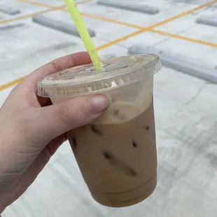 a hand holding a cup of iced coffee