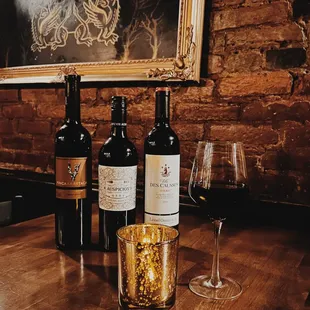 three bottles of wine and a glass of wine