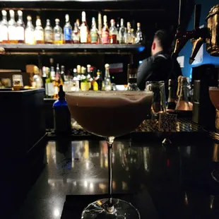 a glass of wine sitting on a bar