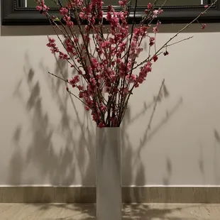 a vase with pink flowers in front of a mirror