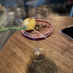 a glass of wine with a lemon garnish