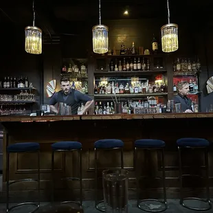 a man behind a bar with blue stools