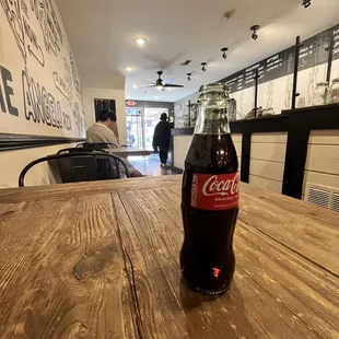 a bottle of coke on a wooden table