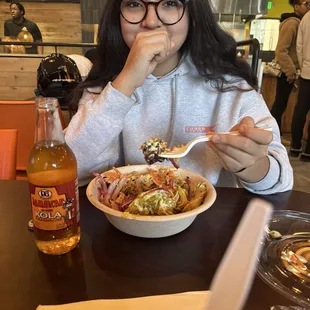 Curry Chicken Bowl with fried rice, sliced red onion, cucumber salad, plantains, avocado sour cream, corn,and carrots.