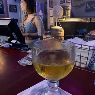 a woman sitting at a bar with a glass of beer