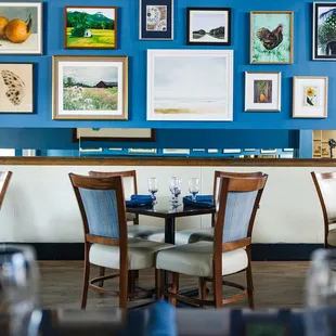a dining room with blue walls and pictures on the wall