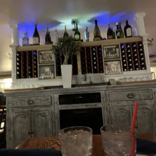 a table with a glass of water and a vase of flowers