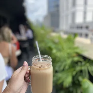 a hand holding a glass of iced coffee