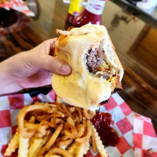 a hand holding a sandwich and french fries